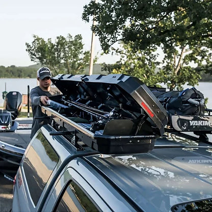 Man loading fishing rods into Yakima TopWater cargo box on truck roof